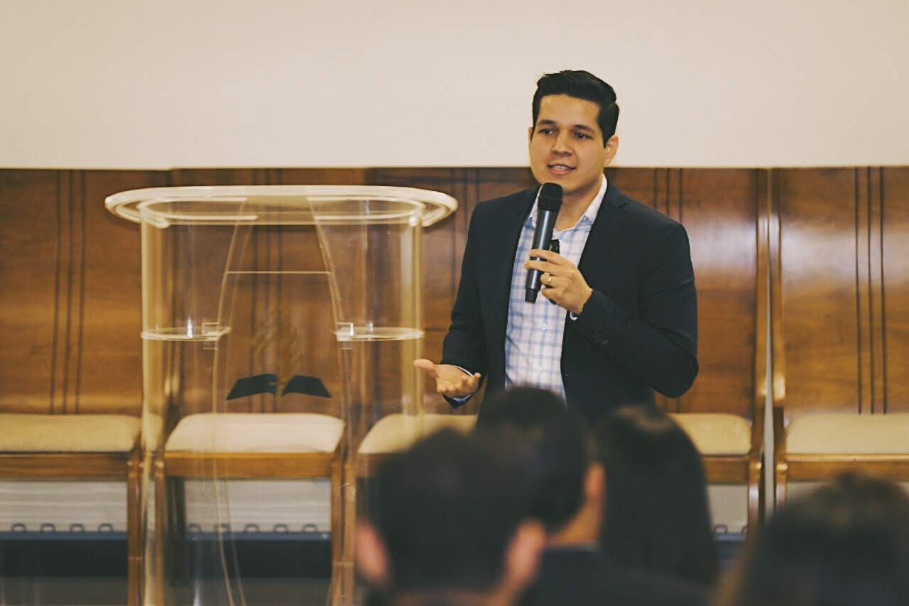 Geyvison Ludugério speaking to a congregation with a microphone