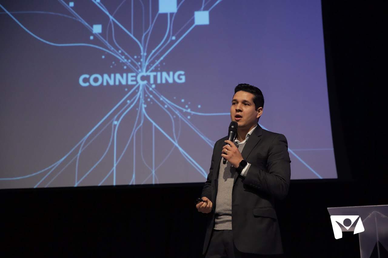 Geyvison Ludugério speaking in front of a 'Connecting' presentation slide
